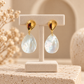 Boucles d’oreilles nacrées sur présentoir beige