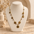 Collier fleurs doré sur petit présentoir beige