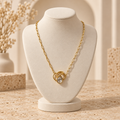 Collier doré avec pendentif cristal sur petit présentoir beige